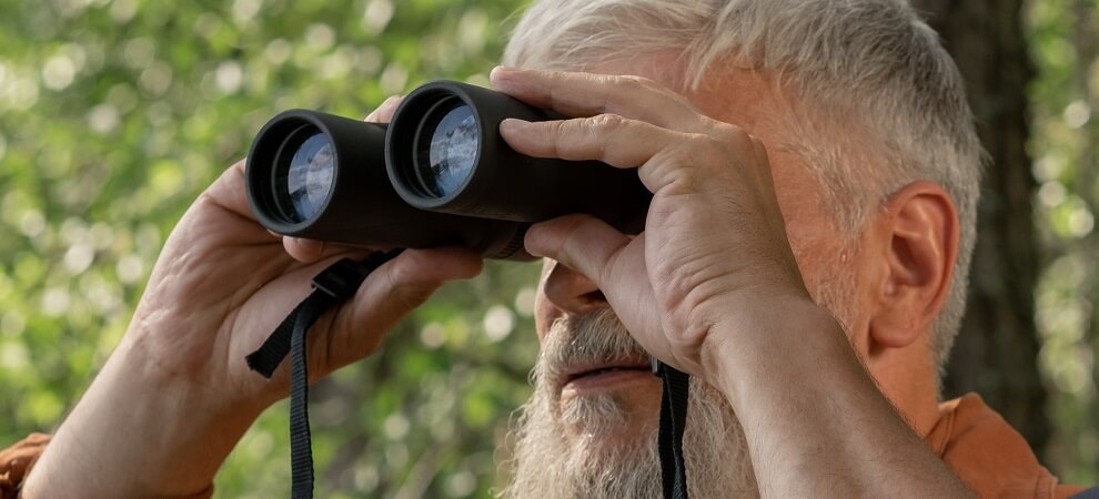 elderly man using binoculars during springtime activities