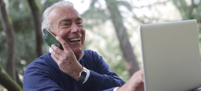 elderly man using a mobile phone and laptop which are essential technology for over-65s